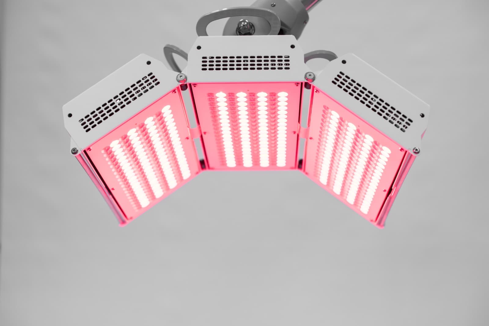 Les trois panneaux de photobiomodulation LED du centre, allumés en lumière rouge